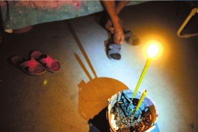 26日,蘆山縣龍門鄉(xiāng)隆興村村民張德文在帳篷中點(diǎn)燃香燭。他的妻子在地震中不幸遇難。 新華社發(fā)